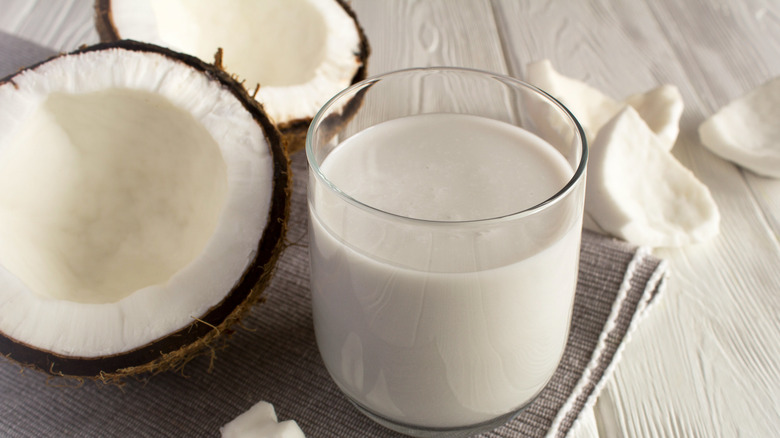 Glass of coconut milk with split coconut