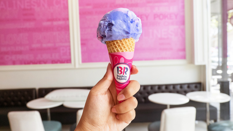 A hand holds a Baskin-Robbins ice cream cone.