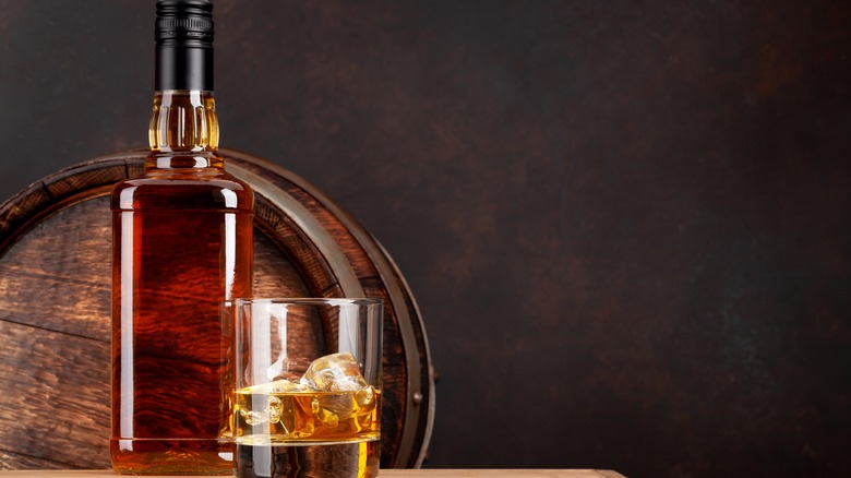 Glass of Scotch whisky on the rocks with a bottle
