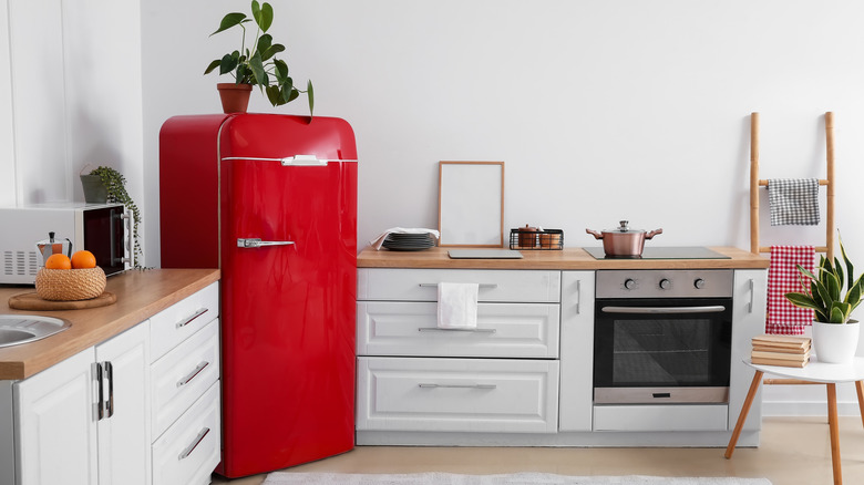 Red retro-style refrigerator in corner of a white kitchen