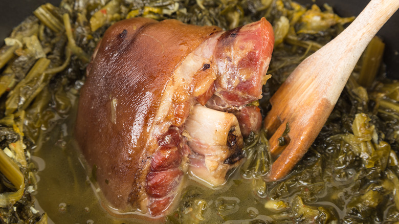 Pot of collard greens cooking with ham hock