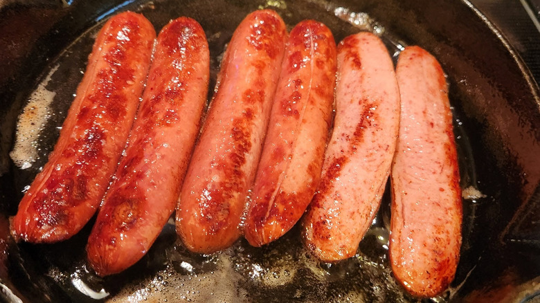 Hot dogs are frying in bacon fat.