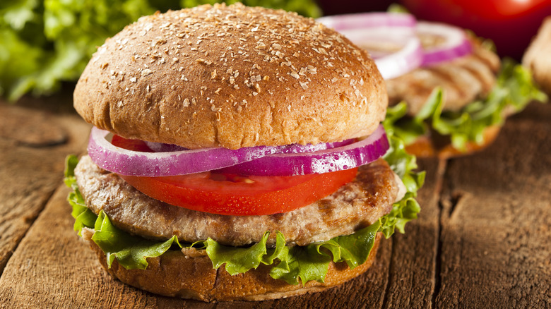 A turkey burger with lettuce, tomatoes, and onions