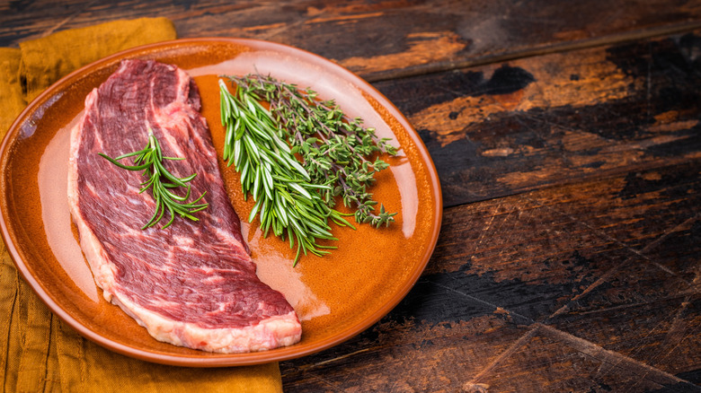 Uncooked sirloin with rosemary and thyme.
