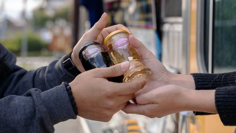 Two people holding cups of Copa di Vino