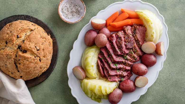 Corned beef with cabbage, carrots, and potatoes on a plate next to bread