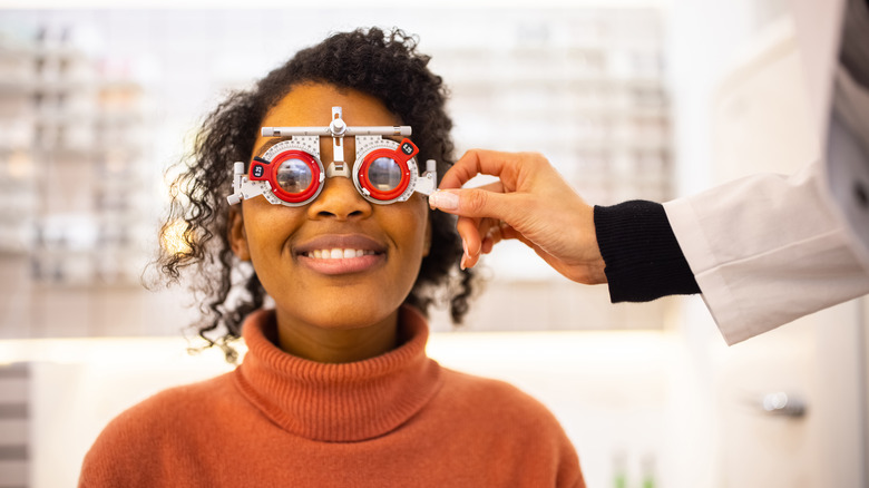 Woman in orange turtleneck receiving an eye exam