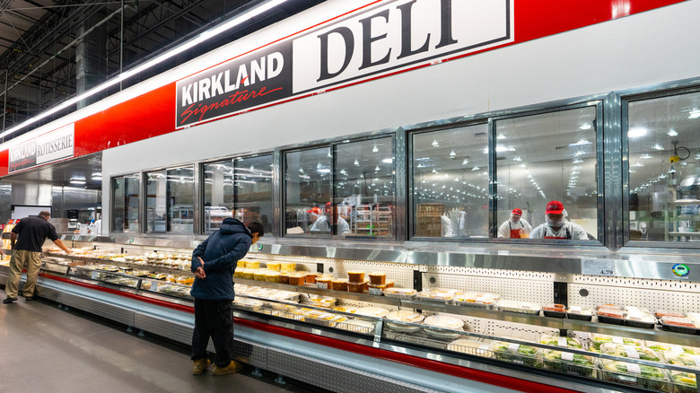A Costco shopper browses the prepared foods in the deli section.