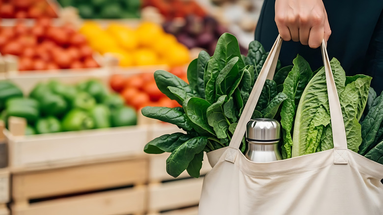 A shopper holds a reusable bag full of groceries
