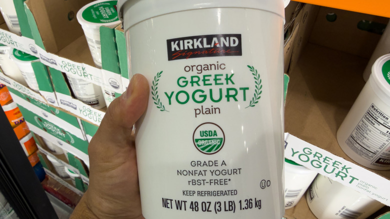 Hand holding container of Kirkland Signature Greek Yogurt