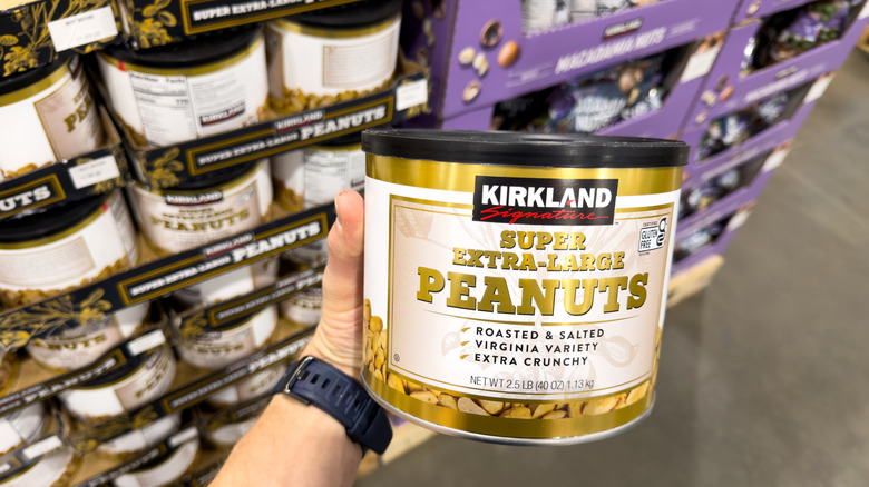 Hand holding container of Kirkland Signature Super Extra Large Peanuts