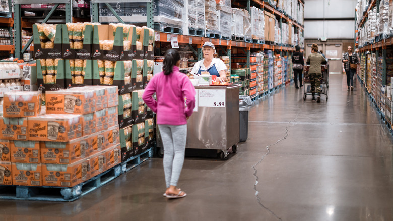 A Costco customer approaches a sampler at a sample station.