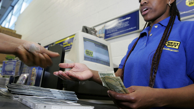 A customer hands money to a Best Buy cashier.