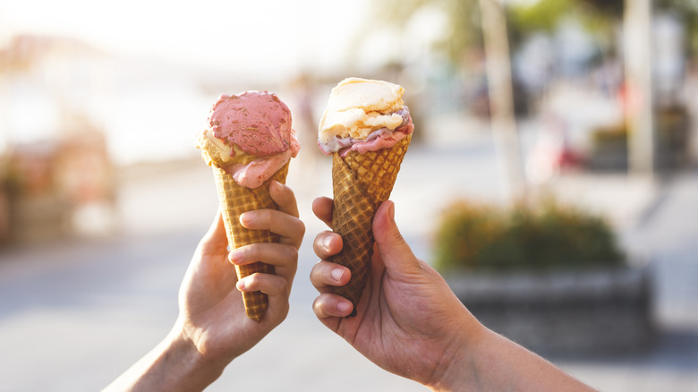 Hands holding ice cream cones.