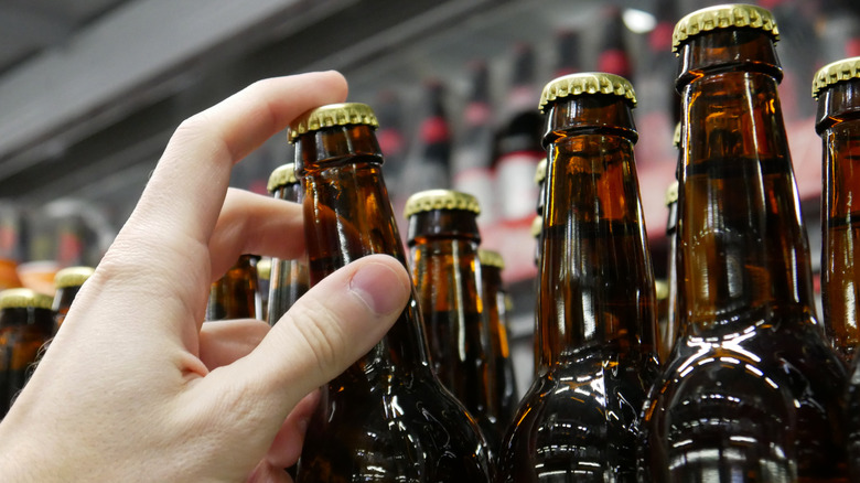 Person grasping a beer bottle.