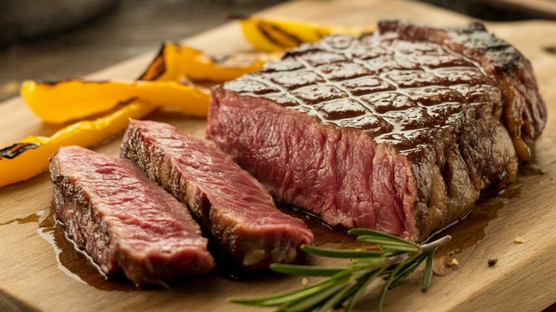 A sliced medium-rare ribeye on a wooden board