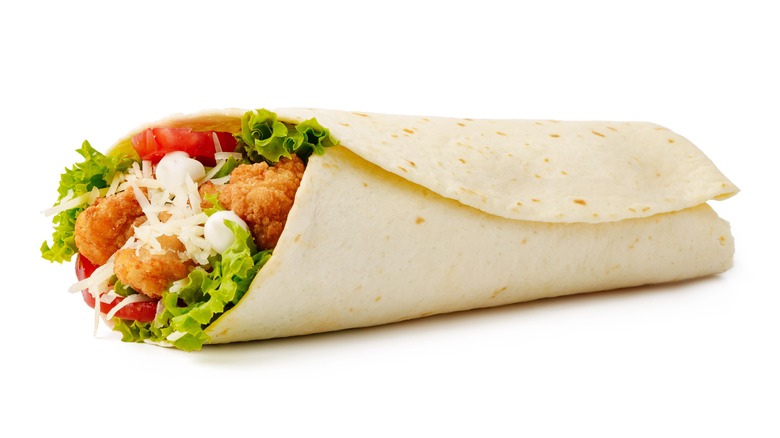 A Snack Wrap-like tortilla filled with chicken, lettuce, and tomato sits against a white background