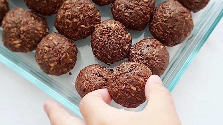 A hand reaching for a chocolate energy bite