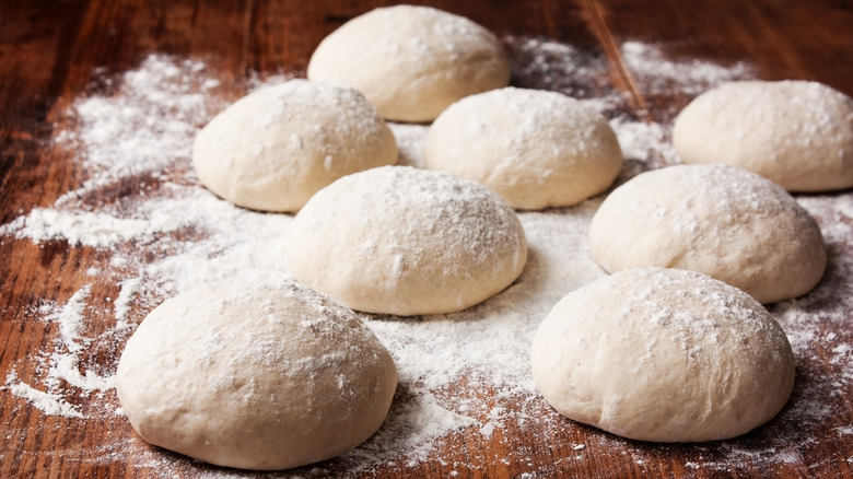 Balls of pizza dough on flour-dusted counter