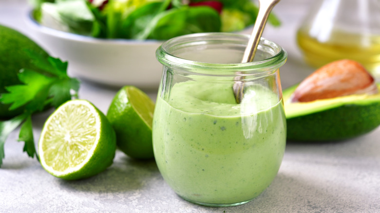 Glass jar of homemade avocado yogurt dressing with fresh lime