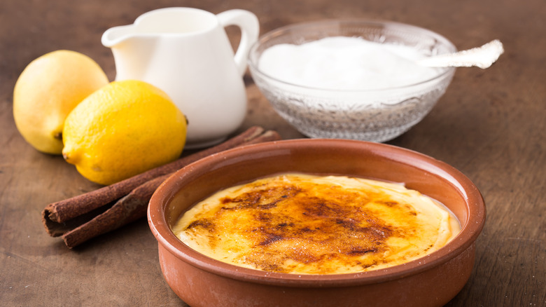 Dish of caramelized dessert, cinnamon stick, lemons, sugar
