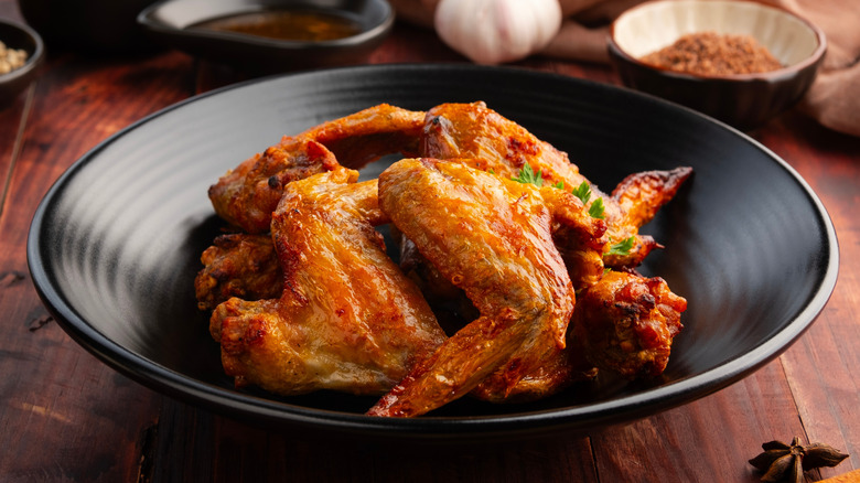 Air-fried chicken wings with crispy skin in a black bowl