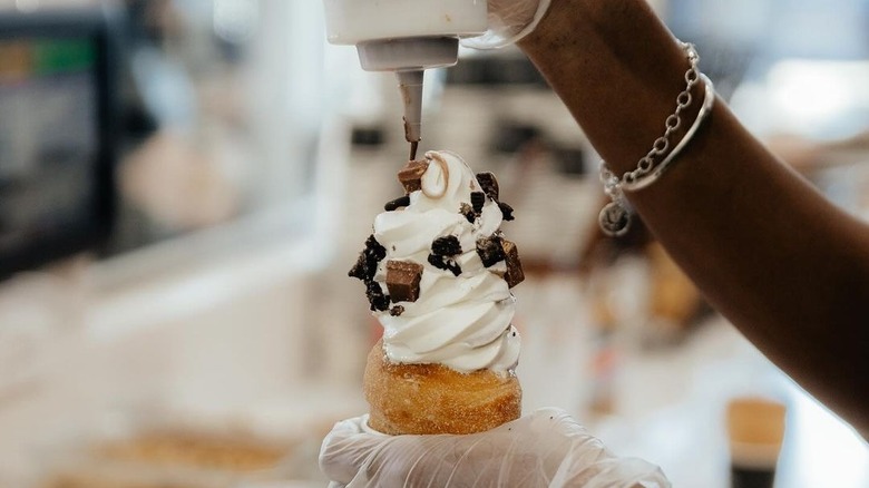 Person adding sauce to ice cream in a Crispy Cone