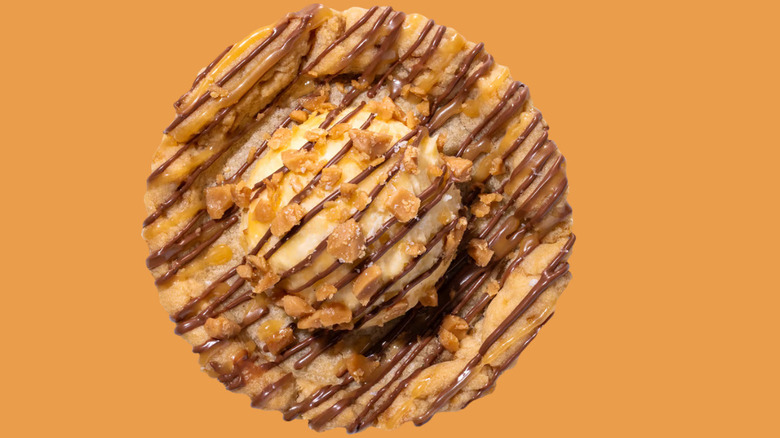 Crumbl's Sea Salt Toffee Skillet Cookie sits, facing forward, against an orange background