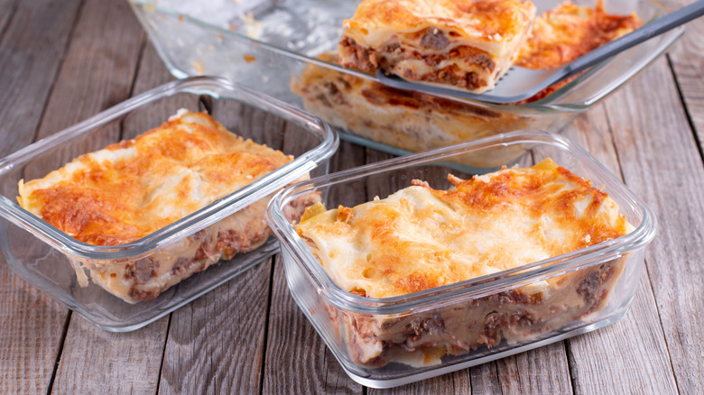 Slices of lasagna in glass dishes on a planked table