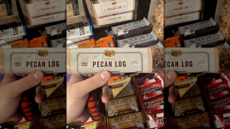Hand holding a Cracker Barrel Pecan Log in front of other candies