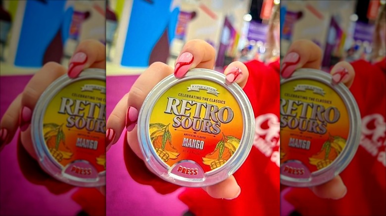 Hand holding a tin of Mango Retro Sours.