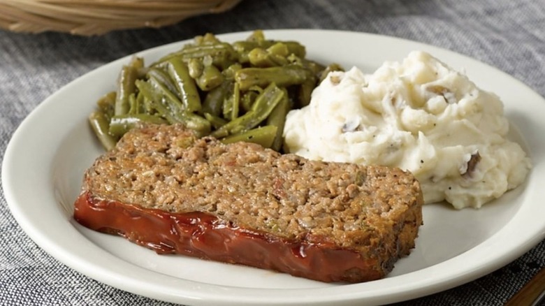 Cracker Barrel server presents a plate of meatloaf with corn and mashed potatoes