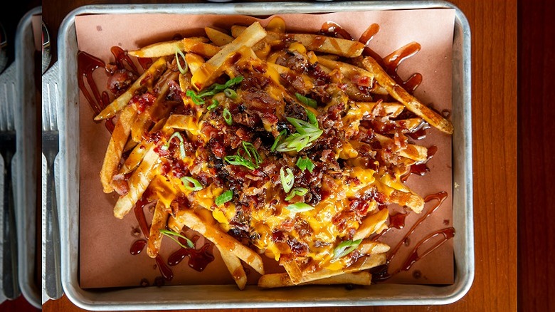 A tray of loaded fries with cheese, bacon, scallions, and sauce