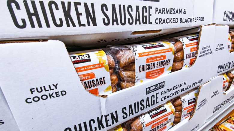 A cart containing multiple packages of Kirkland Signature Chicken Sausage.