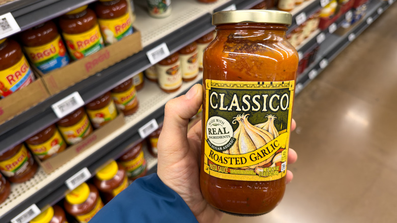 Shopper holding pasta sauce in hand.