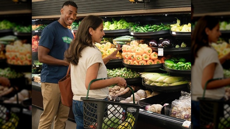 Fresh Thyme Market worker helping a shopper in the produce section.