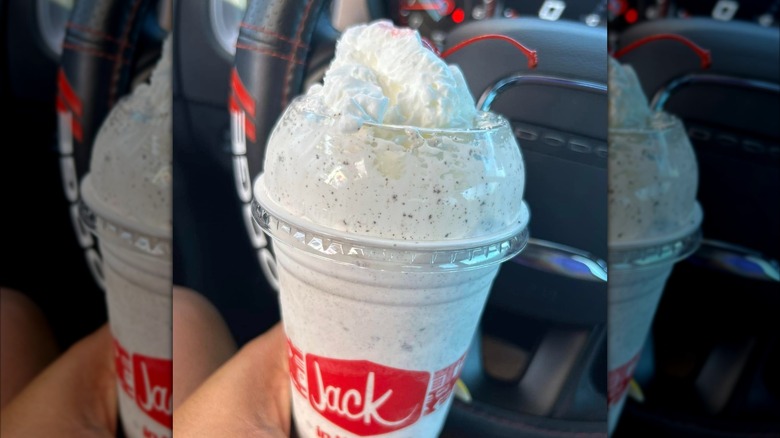 Someone holding a Jack in the Box milkshake in a car