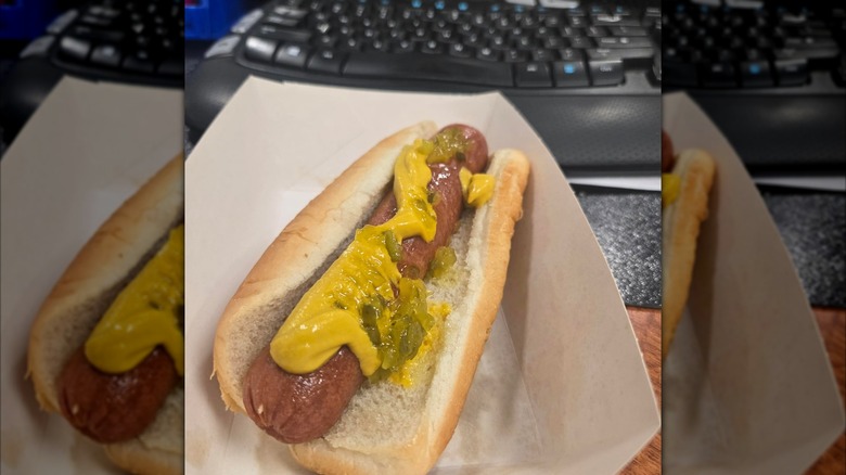 a hot dog with toppings in front of a keyboard