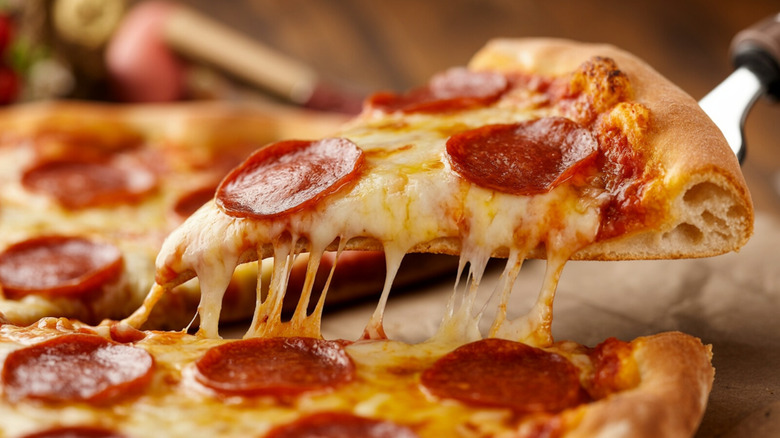 A slice of pepperoni pizza is lifted from the pie with a spatula