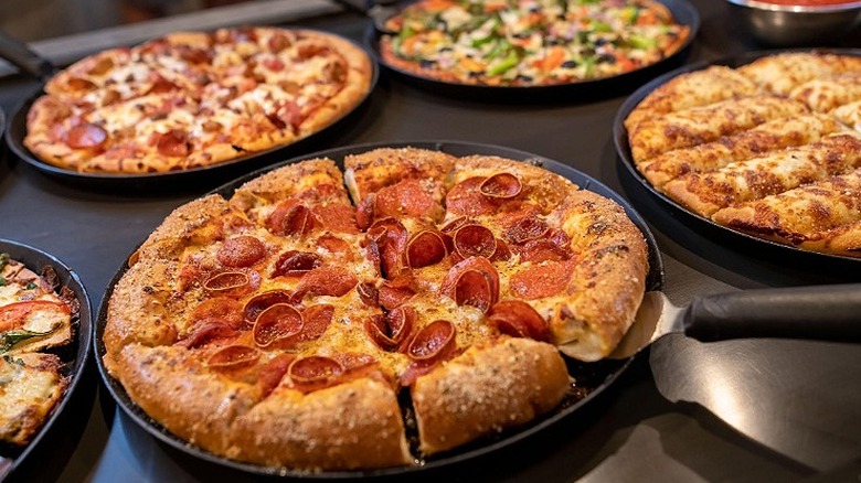 An array of pizzas sit on a buffet table at Pizza Ranch