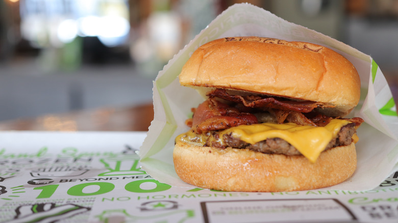 A bacon cheeseburger sits on a paper wrapper at BurgerFi