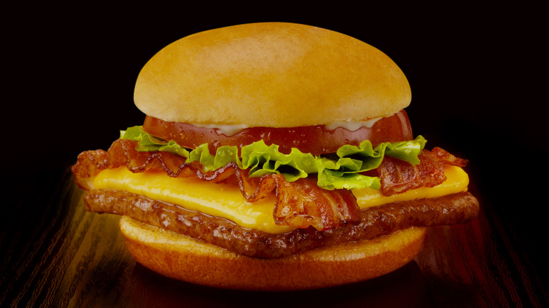 A Wendy's bacon cheeseburger sits against a black background