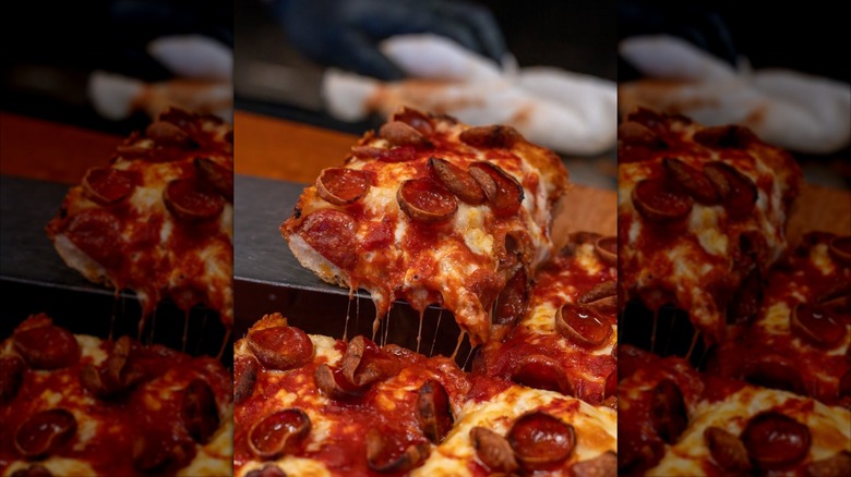 Slice of Detroit-style pizza lifted above other slices