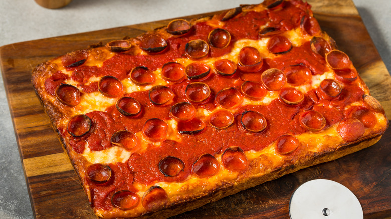 Detroit-style pizza on a wooden cutting board.