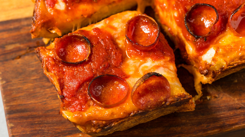 Slices of pepperoni Detroit-style pizza on cutting board
