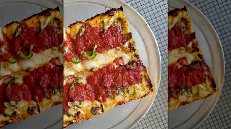 Corner of Detroit-style pizza on a silver tray.