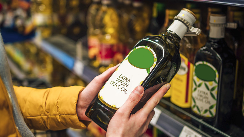 Hands holding olive oil in supermarket