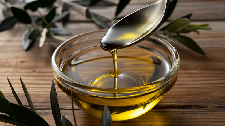 Olive oil in spoon over bowl