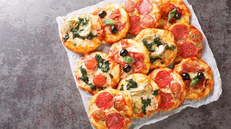 Mini pizzas piled on parchment paper