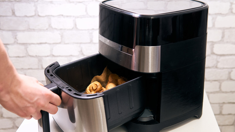 person placing dough balls in air fryer basket